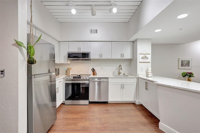 kitchen with light wood-style flooring, appliances with stainless steel finishes, visible vents, light countertops, and track lighting