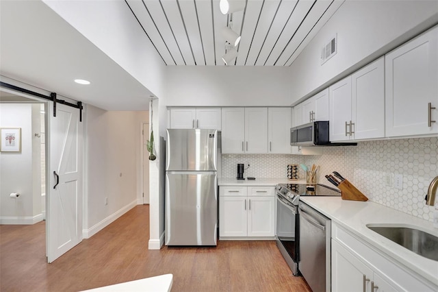 kitchen with a sink, appliances with stainless steel finishes, visible vents, light countertops, and light wood finished floors