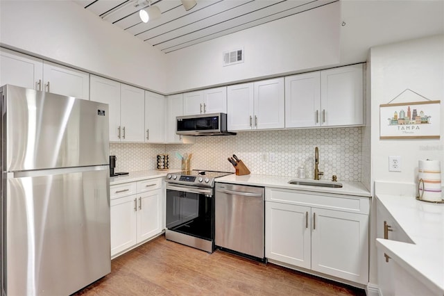 kitchen featuring appliances with stainless steel finishes, white cabinetry, light countertops, and a sink