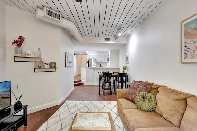 living room with baseboards, visible vents, and wood finished floors