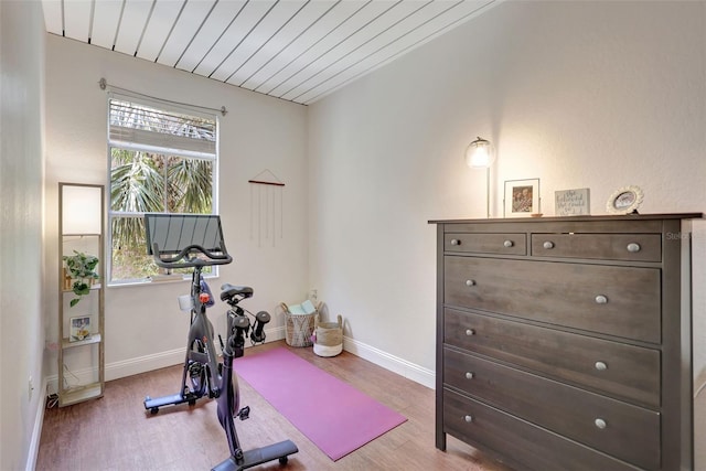 exercise room featuring wooden ceiling, wood finished floors, and baseboards