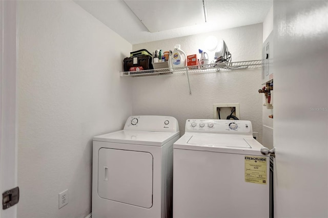 laundry room featuring separate washer and dryer, a textured wall, and laundry area