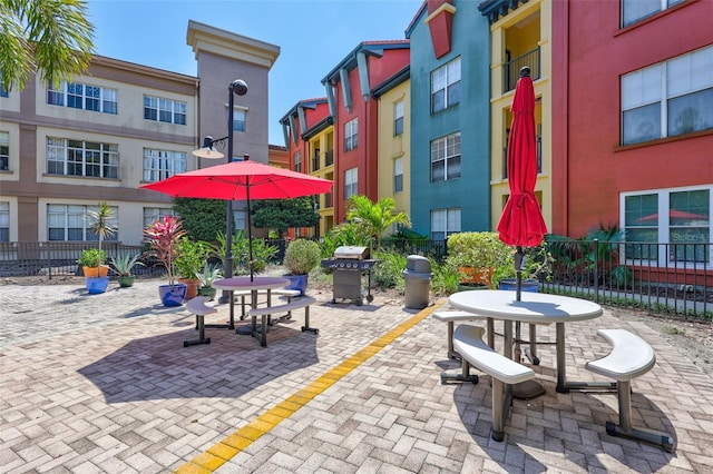 view of community with a patio, outdoor dining area, and fence