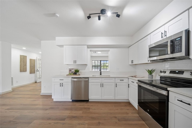 kitchen with stainless steel appliances, a sink, light countertops, white cabinets, and recessed lighting