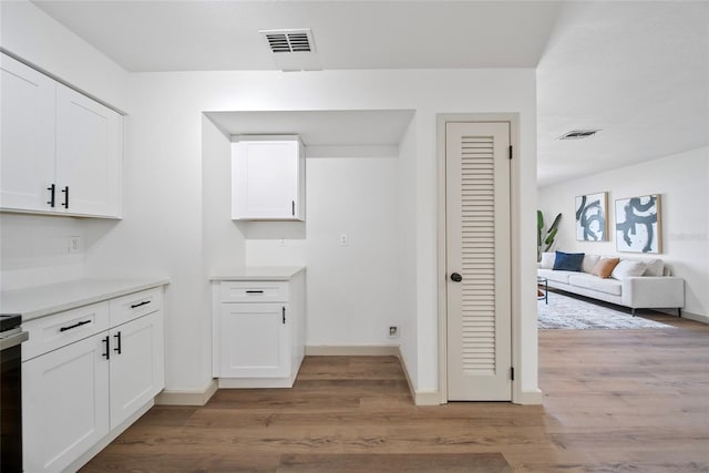 kitchen with white cabinetry, light wood-style flooring, light countertops, baseboards, and open floor plan