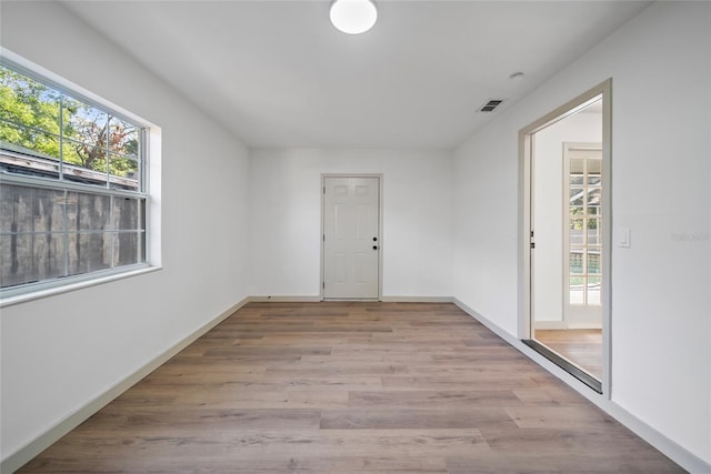 unfurnished room with healthy amount of natural light, wood finished floors, and baseboards