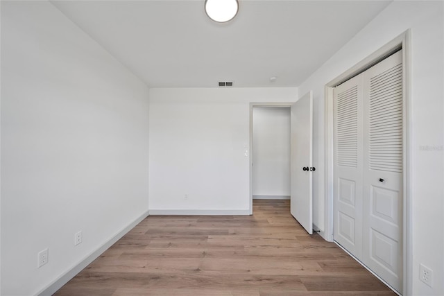 unfurnished bedroom featuring a closet, light wood finished floors, and baseboards
