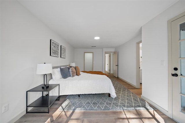 bedroom featuring wood finished floors, baseboards, and recessed lighting