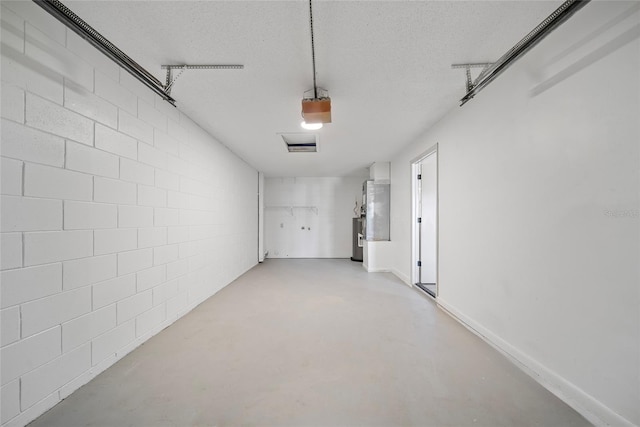 garage with a garage door opener, water heater, and concrete block wall