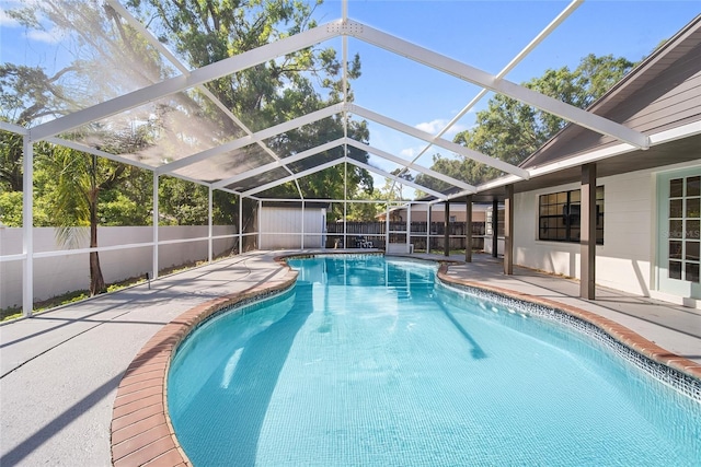 view of pool with a fenced backyard, a patio, glass enclosure, and a storage unit
