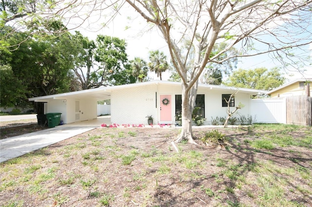 ranch-style home featuring brick siding, fence, driveway, and an attached carport