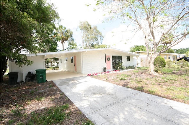 ranch-style house with concrete driveway, brick siding, and an attached carport