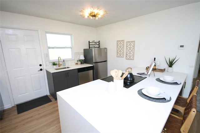 kitchen with a sink, light countertops, a peninsula, dark cabinets, and stainless steel appliances