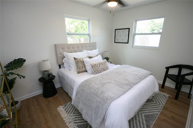 bedroom featuring baseboards, wood finished floors, and multiple windows