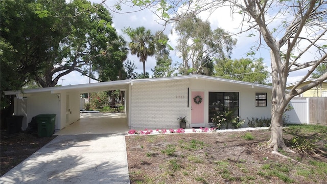 single story home with brick siding, fence, an attached carport, and concrete driveway