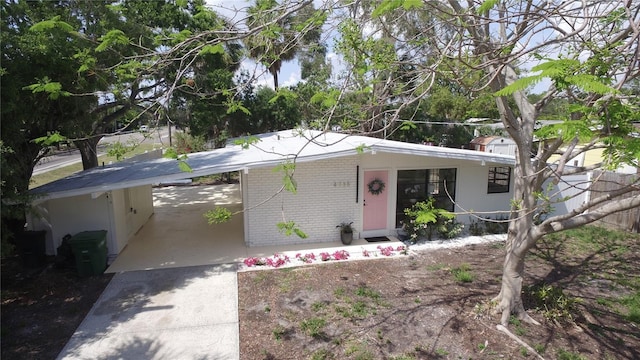 single story home featuring brick siding, driveway, and a carport