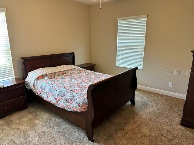 bedroom featuring light carpet and baseboards