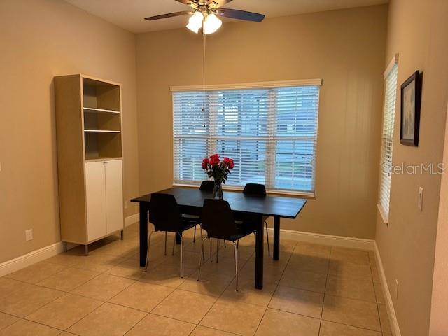 dining space featuring light tile patterned flooring, baseboards, and a ceiling fan