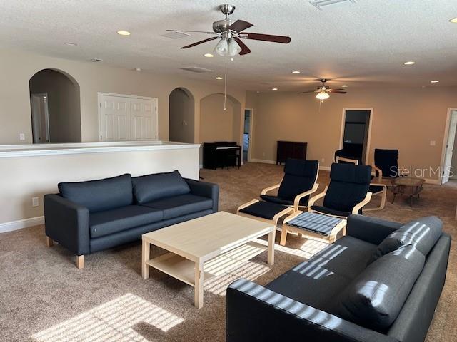 living area featuring carpet floors, arched walkways, ceiling fan, and recessed lighting