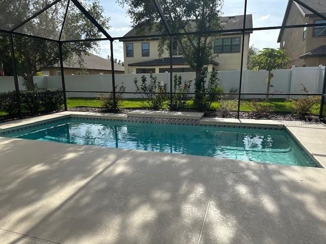 view of pool with a patio, fence, a fenced in pool, and glass enclosure
