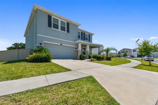 traditional-style house featuring a front lawn, fence, stucco siding, an attached garage, and driveway