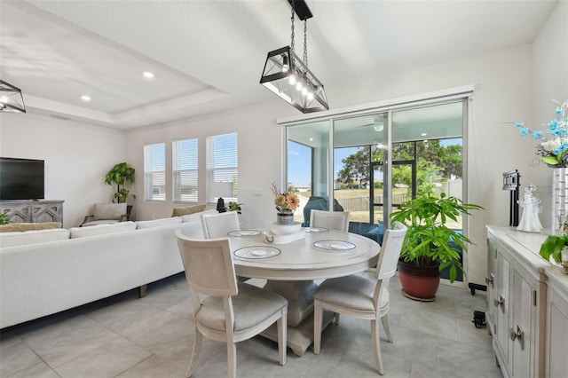 dining space featuring a raised ceiling and light tile patterned floors