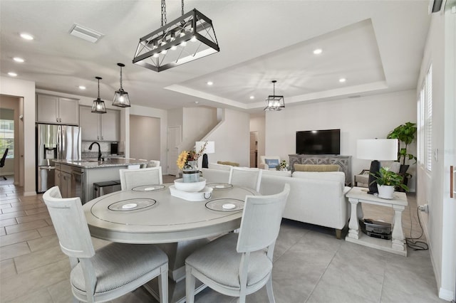 dining space with a tray ceiling, recessed lighting, and visible vents