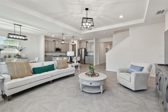 living area with recessed lighting, a raised ceiling, a notable chandelier, and visible vents