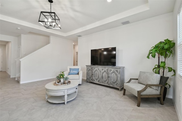 living room featuring visible vents, baseboards, stairway, a tray ceiling, and a notable chandelier