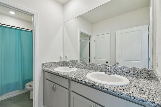 bathroom featuring double vanity, toilet, tile patterned floors, and a sink