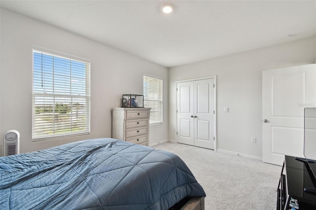 bedroom with baseboards, light carpet, and a closet