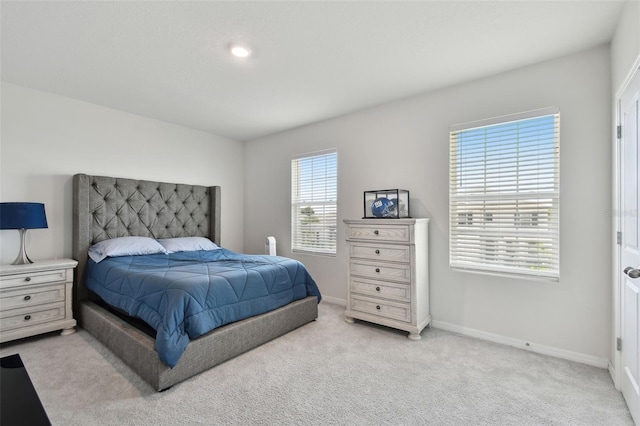 bedroom with baseboards and light colored carpet
