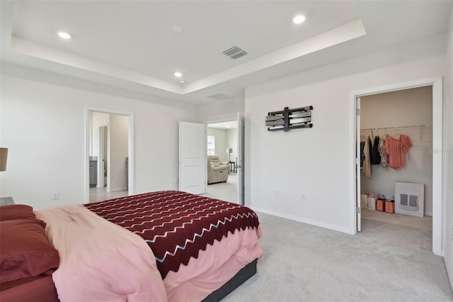 bedroom featuring visible vents, recessed lighting, a tray ceiling, and light carpet