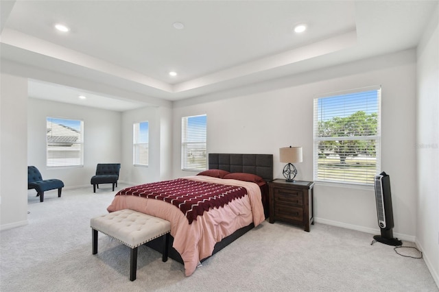 carpeted bedroom featuring recessed lighting, baseboards, multiple windows, and a tray ceiling