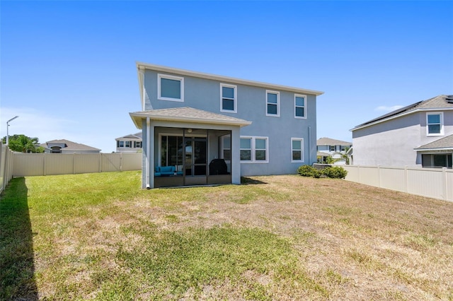 back of house featuring a sunroom, a fenced backyard, a lawn, and stucco siding