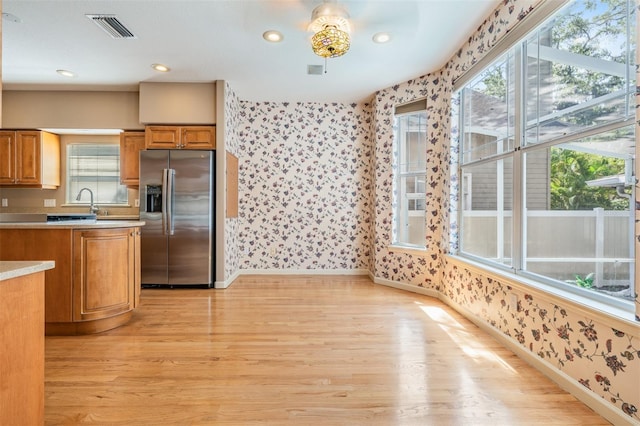 2704 Chambray Ln, Tampa, FL 33611 - kitchen with stainless steel refrigerator with ice dispenser, wallpapered walls, light wood-style flooring, baseboards, and light countertops