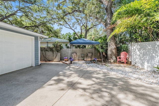 2704 Chambray Ln, Tampa, FL 33611 - view of patio featuring a garage, fence, and driveway