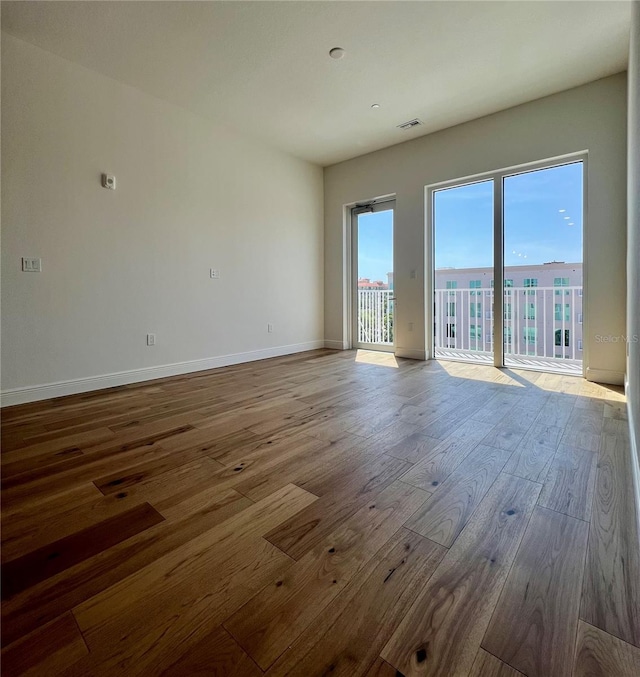 spare room featuring baseboards, wood finished floors, and visible vents