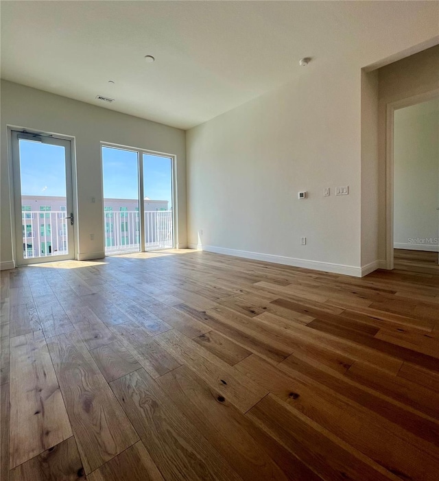 spare room featuring visible vents, baseboards, and wood finished floors