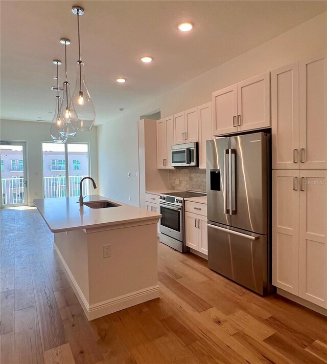 kitchen with backsplash, a sink, light wood finished floors, stainless steel appliances, and recessed lighting