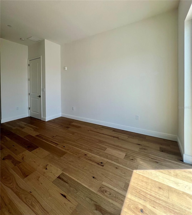 spare room featuring baseboards and wood-type flooring