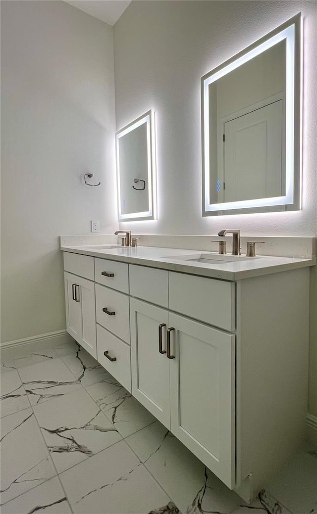 bathroom with double vanity, baseboards, a sink, and marble finish floor