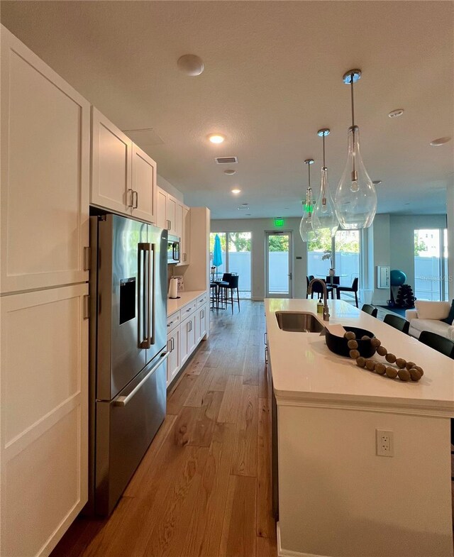 kitchen featuring white cabinetry, appliances with stainless steel finishes, a sink, and light wood-style flooring