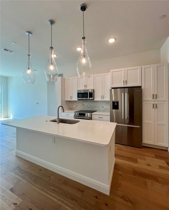 kitchen featuring a sink, white cabinets, stainless steel appliances, and light wood-style flooring