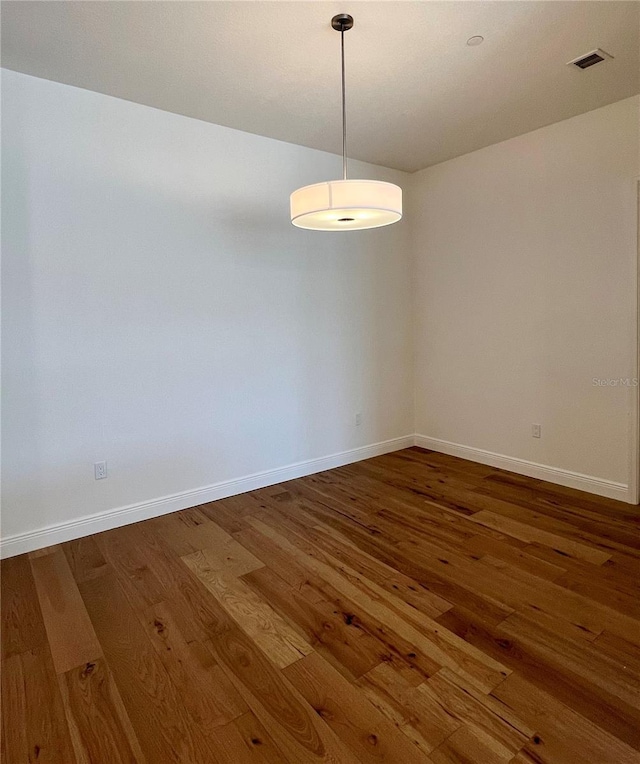 spare room with baseboards and wood finished floors