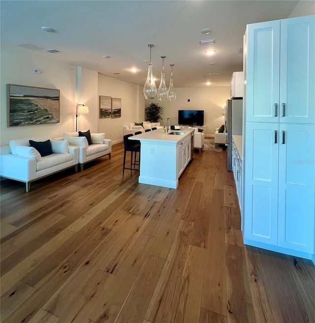 kitchen featuring a sink, white cabinets, hardwood / wood-style flooring, and open floor plan