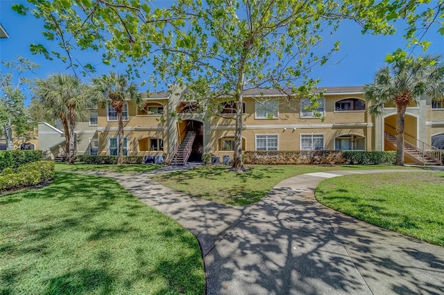 view of front facade featuring a front yard, stairs, and stucco siding