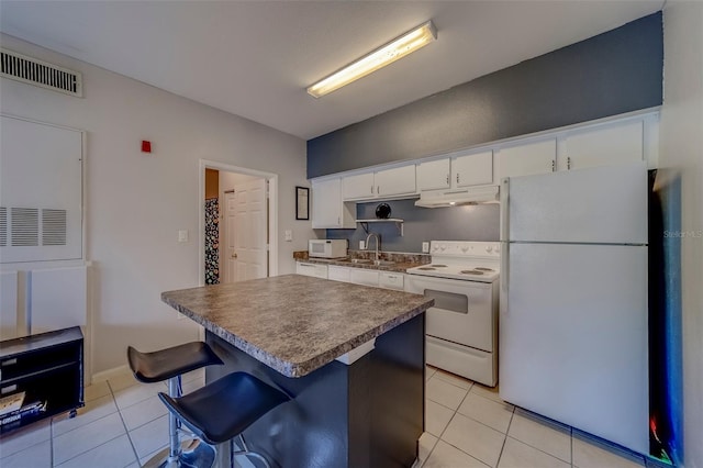 kitchen with visible vents, under cabinet range hood, white appliances, and light tile patterned flooring