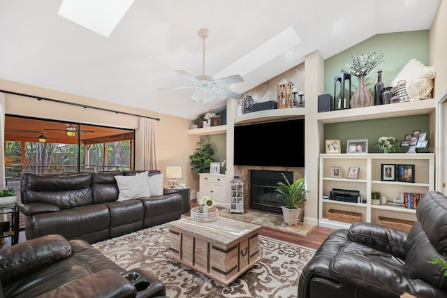 1004 Hollyberry Ct, Brandon, FL 33511 - living room featuring a skylight, vaulted ceiling, a ceiling fan, wood finished floors, and a tiled fireplace