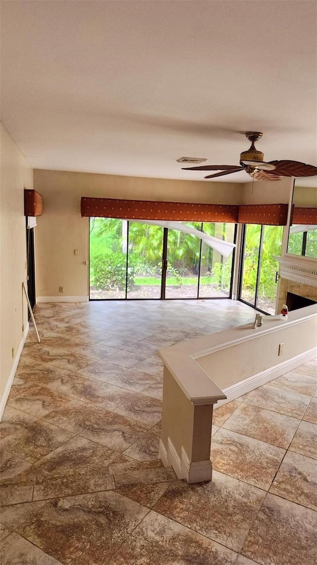17115 Bay St, Jupiter, FL 33477 - unfurnished living room featuring a fireplace, baseboards, a ceiling fan, and plenty of natural light